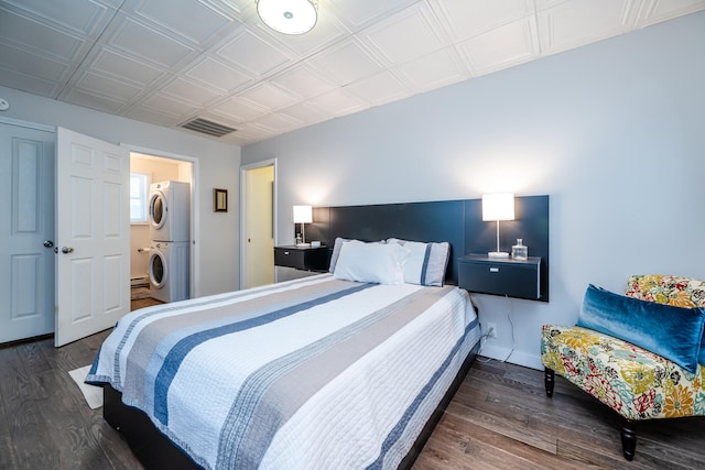 bedroom with stacked washer / drying machine, stainless steel fridge, and dark hardwood / wood-style flooring