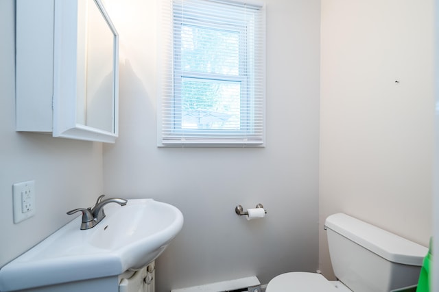 bathroom featuring sink, a baseboard heating unit, and toilet