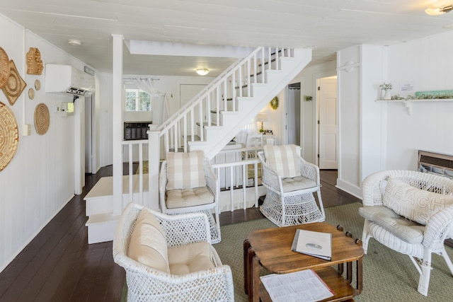 living room with stairway, a fireplace, a wall mounted AC, and hardwood / wood-style flooring