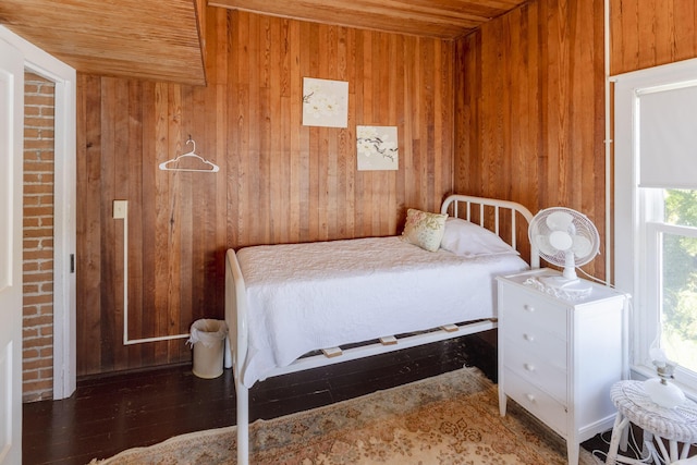 bedroom with wooden walls, wood ceiling, and wood finished floors