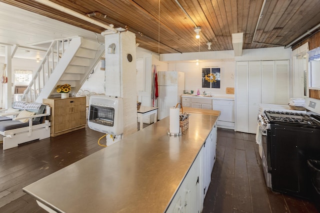 kitchen featuring dark wood-type flooring, stainless steel counters, heating unit, white appliances, and wood ceiling