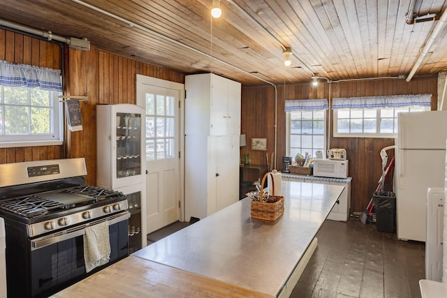 kitchen with stainless steel counters, white appliances, wood ceiling, and wood walls