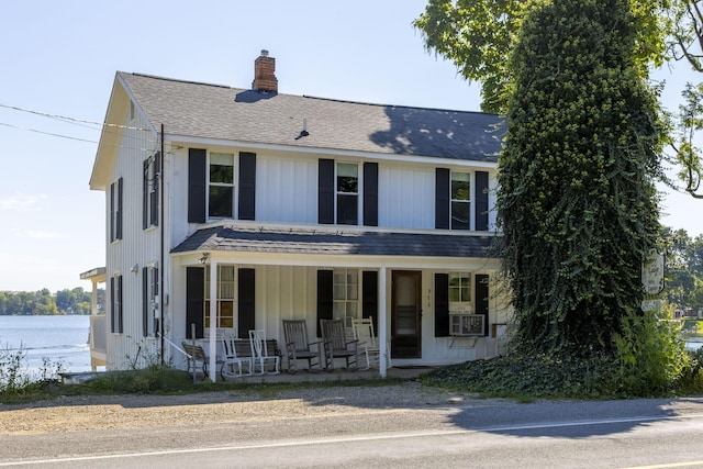 view of front of property featuring a porch, roof with shingles, and a chimney