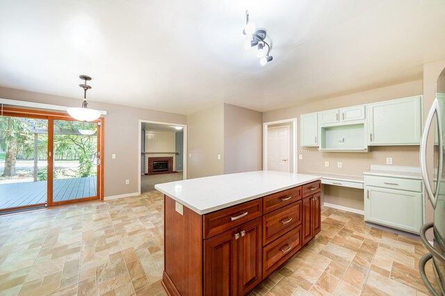 kitchen with a fireplace, stainless steel refrigerator, decorative light fixtures, white cabinets, and a center island