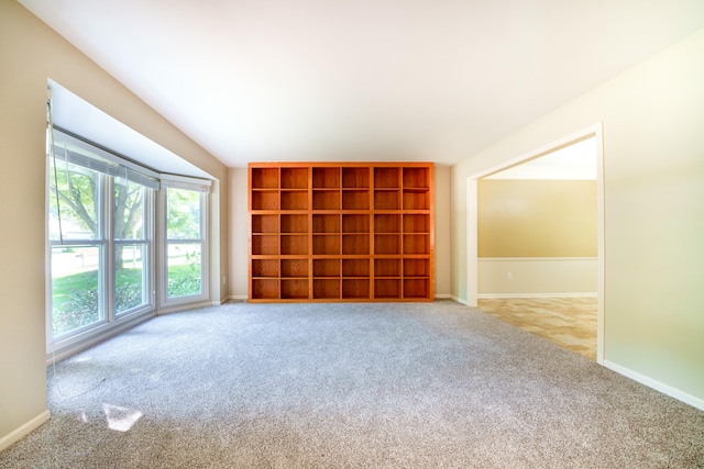 spare room featuring built in shelves, a wealth of natural light, and light colored carpet