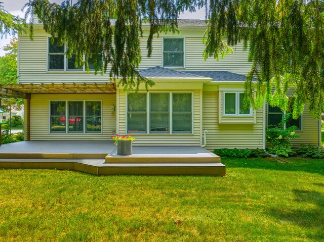 rear view of house featuring a wooden deck and a lawn