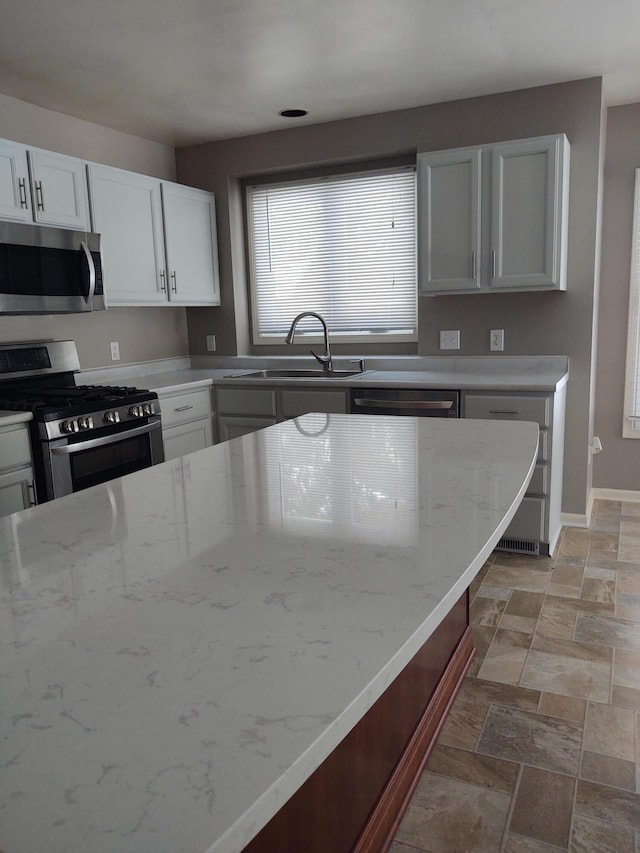 kitchen with white cabinetry, sink, light stone countertops, and appliances with stainless steel finishes