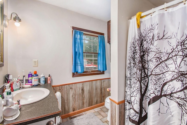 bathroom with wooden walls, visible vents, toilet, a wainscoted wall, and vanity