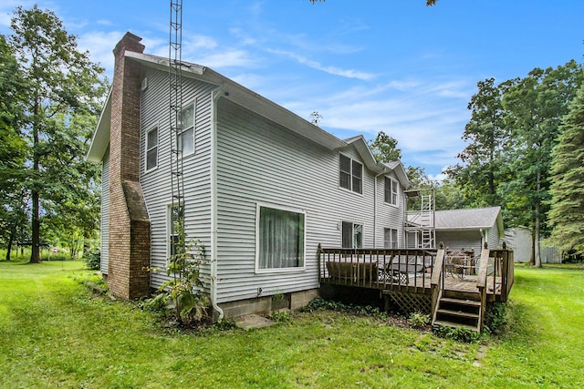 back of property featuring a chimney, a deck, and a yard