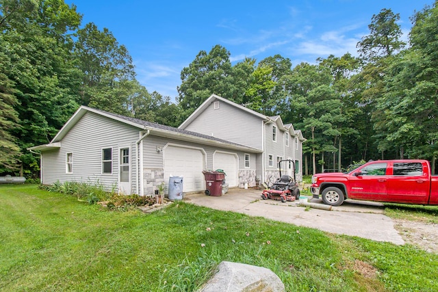 view of side of property with a garage, stone siding, concrete driveway, and a yard