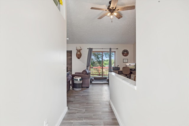 hallway featuring wood-type flooring, vaulted ceiling, and a textured ceiling