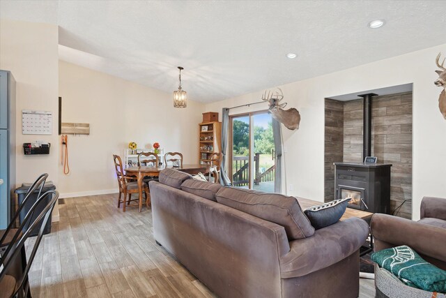 living room with lofted ceiling, light hardwood / wood-style flooring, and a wood stove