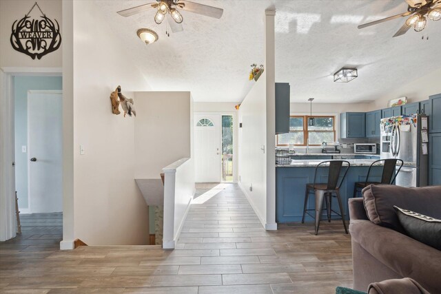 interior space with ceiling fan, a textured ceiling, and light wood-type flooring