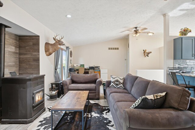 living room featuring a textured ceiling, light hardwood / wood-style floors, vaulted ceiling, and ceiling fan