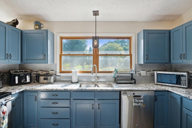 kitchen featuring hanging light fixtures, sink, blue cabinetry, and stainless steel appliances