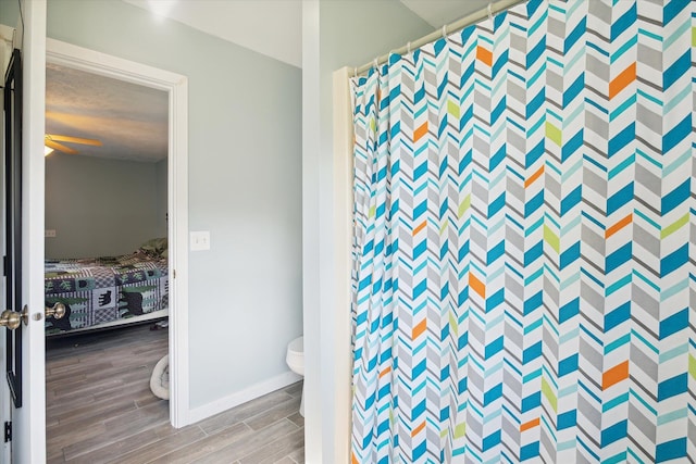 bathroom with wood-type flooring, a textured ceiling, curtained shower, and toilet