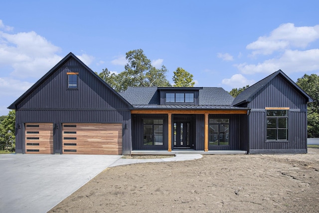 modern farmhouse with driveway, a standing seam roof, roof with shingles, an attached garage, and metal roof