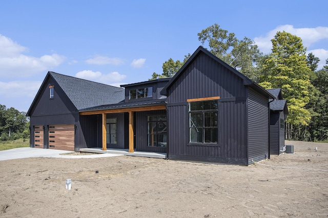 modern inspired farmhouse with central AC, roof with shingles, covered porch, a garage, and driveway