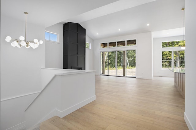 corridor featuring plenty of natural light, an upstairs landing, light wood-type flooring, and high vaulted ceiling