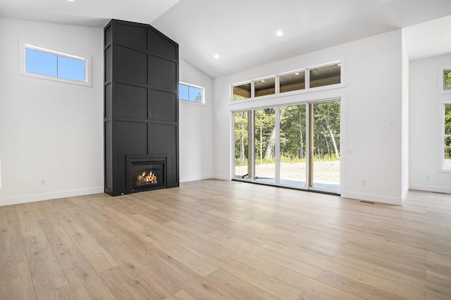 unfurnished living room with light wood finished floors, baseboards, recessed lighting, a fireplace, and high vaulted ceiling