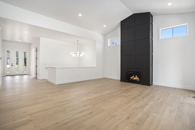 unfurnished living room with a large fireplace, light wood-style floors, an inviting chandelier, and vaulted ceiling