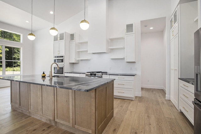 kitchen featuring a sink, light wood-style flooring, a high ceiling, and open shelves