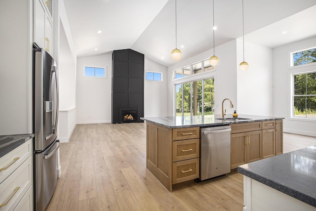 kitchen featuring a sink, a large fireplace, appliances with stainless steel finishes, and light wood-style flooring