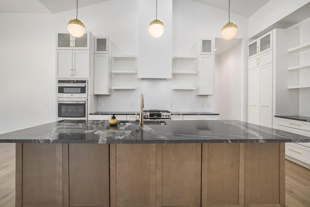 kitchen featuring open shelves, white cabinetry, double oven, and a sink