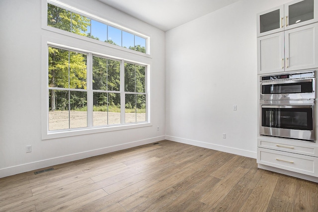 interior space with light wood-style floors, visible vents, and baseboards