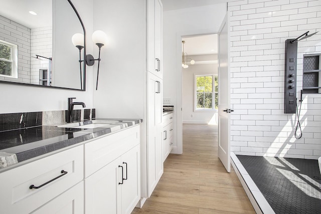 bathroom featuring wood finished floors, recessed lighting, tiled shower, baseboards, and vanity