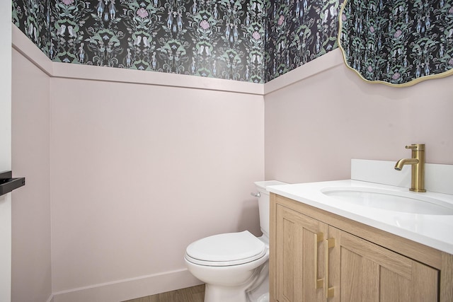 half bath with vanity, toilet, and baseboards