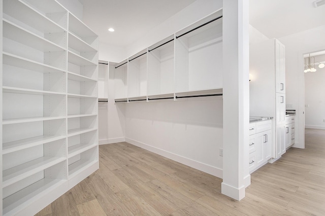 walk in closet with light wood-style floors