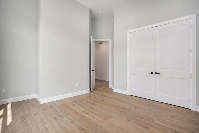 unfurnished bedroom featuring a closet, visible vents, light wood-type flooring, and baseboards