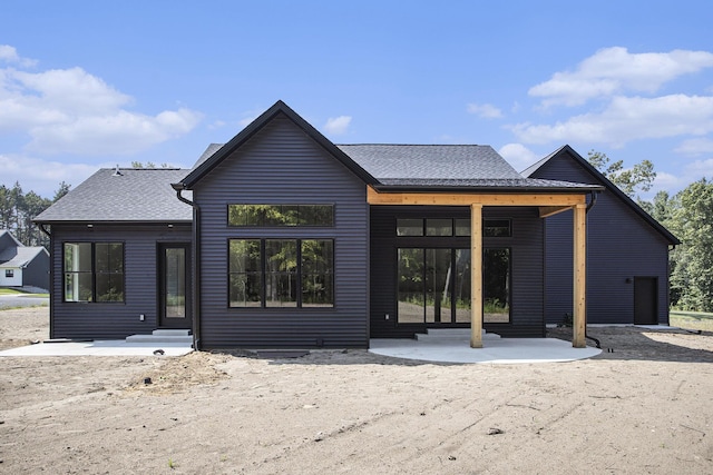 back of property featuring roof with shingles and a patio area