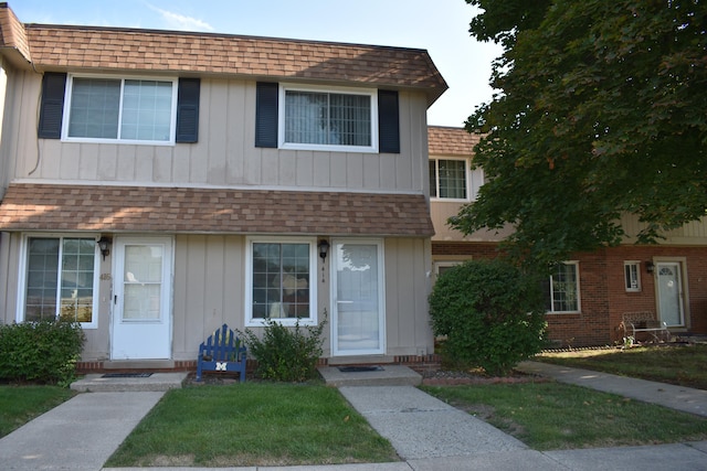 view of front of property featuring mansard roof, brick siding, and a shingled roof