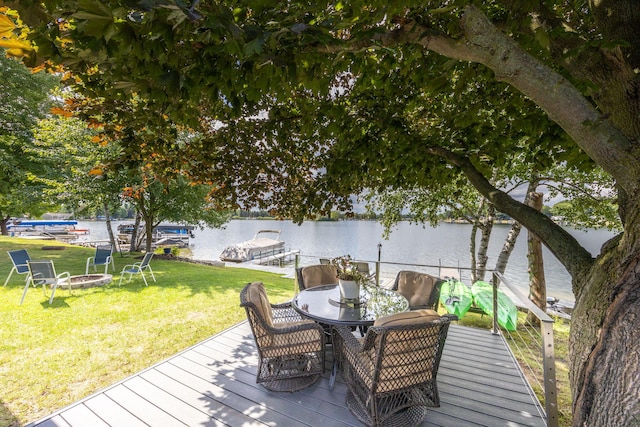 wooden terrace with a water view, a dock, and a lawn