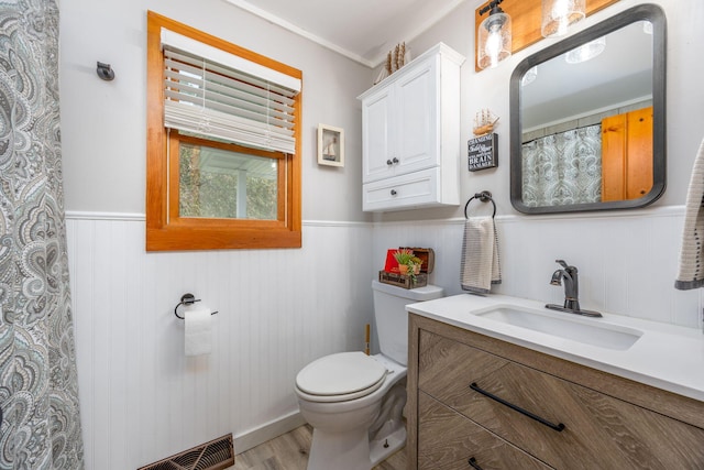 bathroom with hardwood / wood-style flooring, wooden walls, toilet, vanity, and ornamental molding