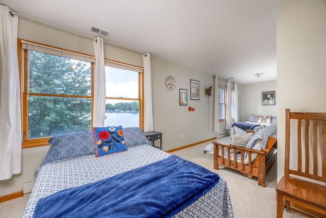 carpeted bedroom featuring a water view and baseboard heating