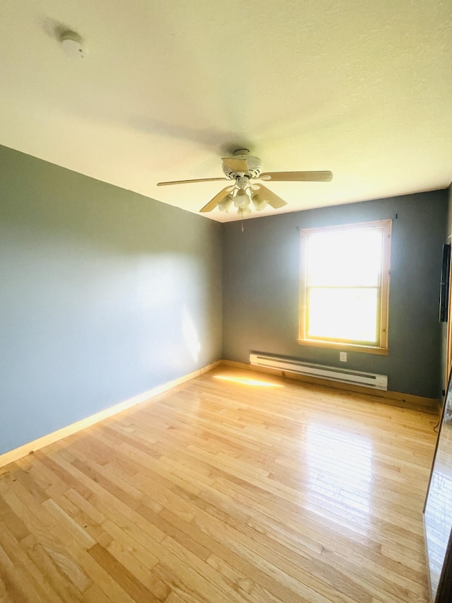 empty room with light wood-style floors, baseboards, baseboard heating, and a ceiling fan