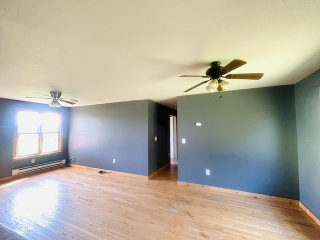 spare room featuring a baseboard radiator, wood finished floors, and baseboards