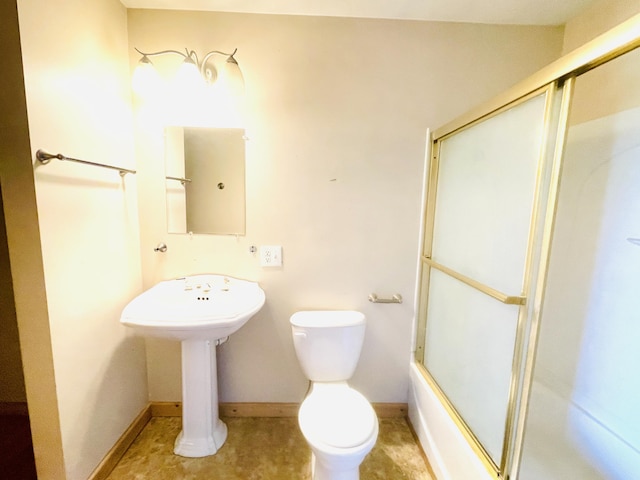 bathroom with combined bath / shower with glass door, a sink, toilet, and baseboards