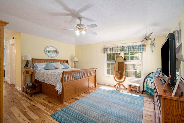 bedroom with ceiling fan, a textured ceiling, and light hardwood / wood-style flooring