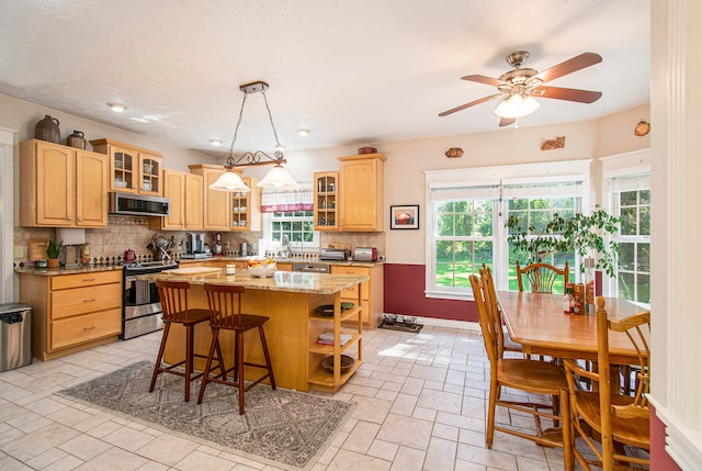 kitchen featuring appliances with stainless steel finishes, tasteful backsplash, a healthy amount of sunlight, and a center island