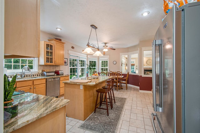 kitchen with appliances with stainless steel finishes, sink, a healthy amount of sunlight, and a center island