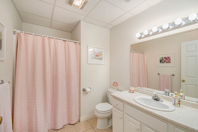 bathroom featuring toilet, vanity, a drop ceiling, and tile patterned flooring