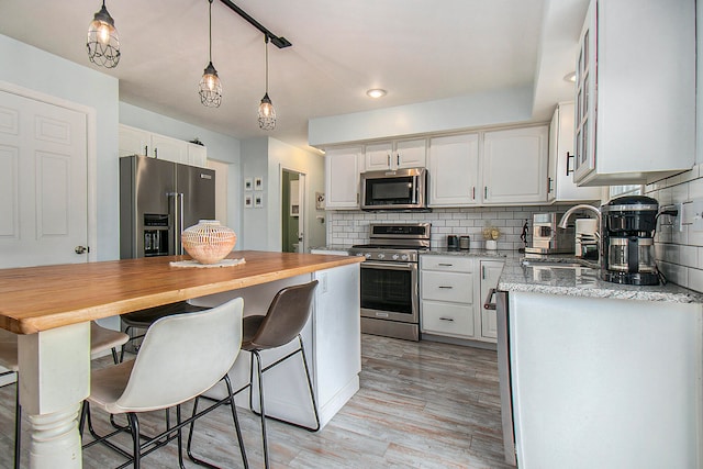 kitchen with white cabinetry, backsplash, stainless steel appliances, and sink