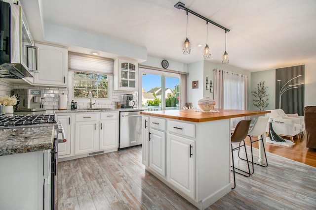 kitchen featuring white cabinetry, a center island, decorative backsplash, appliances with stainless steel finishes, and light hardwood / wood-style floors