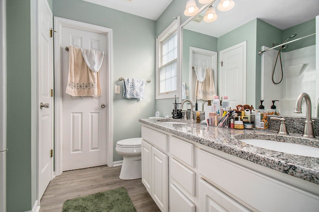 bathroom with hardwood / wood-style floors, walk in shower, toilet, and vanity