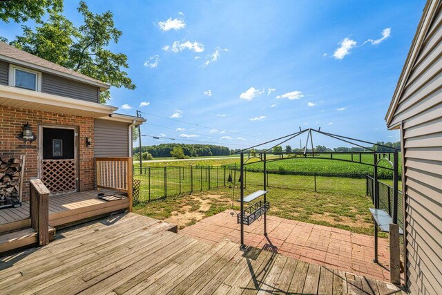 wooden deck with a rural view and a lawn