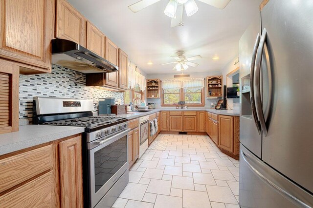 kitchen with ceiling fan, decorative backsplash, wall chimney exhaust hood, appliances with stainless steel finishes, and light tile patterned flooring